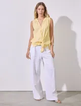 Blusa amarilla sin mangas de lino y rayón, con cuello a la base y escote en V, abertura central con botones y terminación anudada.