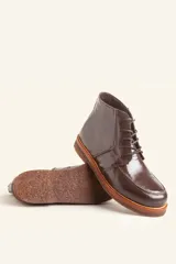 Bota acordonada de cuero vacuno con acabado charol color suela, con suela de goma tipo crepe y costuras reforzadas.