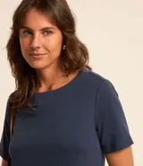 Vestido corto marrón oscuro, estilo camiseta, con escote redondo, mangas cortas y bolsillos laterales. El bajo es redondeado.