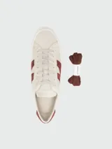 Zapatillas bajas Moncler modelo Moncado2, color crema, con franjas laterales en gamuza color bordó que forman una 'M' y la palabra 'MONCLER' grabada. Tienen cordones grises y suela de goma blanca.