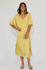 Vestido amarillo de lino con escote en V y mangas cortas con terminación desflecada. Corte recto con aberturas laterales y ruedo desflecado.