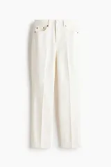 Jean tobillero de corte slim straight y tiro alto, en denim de algodón blanco con ligero stretch, cinco bolsillos, cierre de botón y cremallera, y pliegues marcados al frente y en la espalda.