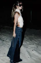 Jeans de corte wide leg en denim negro lavado, con inserción lateral de encaje negro adornado con flecos y lentejuelas.