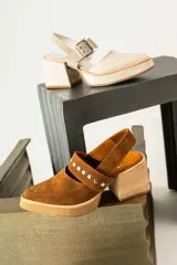 Zapatos tipo zueco de gamuza negra con punta fina y tira sobre el empeine decorada con tachas metálicas plateadas. Posee taco cuadrado de madera y suela con plataforma.