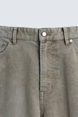 Pantalón de pana de corte flare, color verde oliva desgastado, con cinco bolsillos y cierre frontal de cremallera y botón.