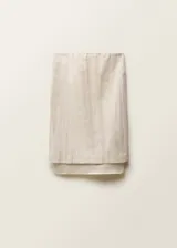 Falda midi de diseño recto y tiro medio, confeccionada en una mezcla de algodón y lino. Presenta cintura con elástico, abertura posterior en el bajo y un forro interior visible de ramio que sobresale del ruedo.