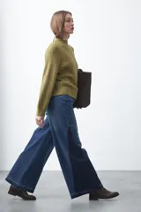 Polera de punto color marrón, con cuello alto y diseño de trenzas verticales en el frente y tejido acanalado en las mangas. Presenta mangas raglán y terminaciones acanaladas en puños y ruedo.