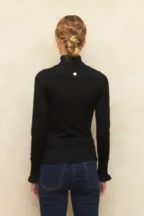 Polera de tejido fino color negro, con cuello alto y mangas largas con terminación sutilmente fruncida. Diseño ajustado al cuerpo.