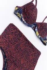 Bikini de dos piezas en combinación de colores negro y mostaza. El corpiño es de estilo triangular con base y breteles finos, mientras que la bombacha es de corte clásico con cintura alta en color negro.