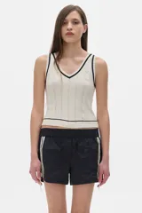 Musculosa tejida color crema con cuello en V y ribete negro.