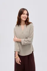 Blusa de viscosa color beige con cuello en V, cierre parcial de botones frontales, bolsillo en el pecho y mangas 3/4.