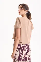 Blusa de manga corta con pliegues en escote redondo, confeccionada en tela crepé de color beige.
