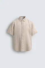 Camisa de lino color beige de corte relajado, con cuello solapa, manga corta y cierre frontal con botones.