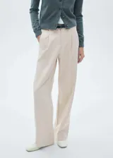 Pantalon de vestir color beige, de corte recto y tiro medio. Presenta detalle de pinzas en la parte frontal, bolsillos laterales y cierre oculto con botón, gancho y cremallera.