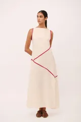 Vestido largo de lino 100% color beige, con cuello semi-bote, sin mangas y detalles de vivos en color rojo a contratono con líneas diagonales.