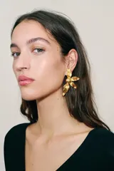 Pendientes metálicos dorados con diseño de flor en relieve y acabado texturizado.