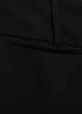 Pantalon de vestir negro de corte acampanado, con tiro bajo y cierre oculto. Presenta diseño de traje con bolsillos de ribete en la parte posterior.