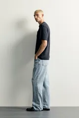 Jeans flare fit de denim negro, tiro medio, ajustados arriba y con botamanga acampanada. Cuentan con cinco bolsillos, lavado efecto gastado y bajo con acabado irregular. Cierre frontal con cremallera y botón.