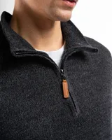 Buzo de tejido de punto negro, con cuello alto y cierre frontal parcial.