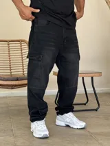 Pantalón tipo cargo de denim color negro con efecto lavado. Presenta corte holgado, bolsillos laterales con solapa y costuras reforzadas en las rodillas.