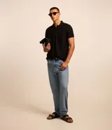 Pantalón de jeans denim celeste, corte slim, con cintura fija con trabillas, bolsillos y pespuntes.