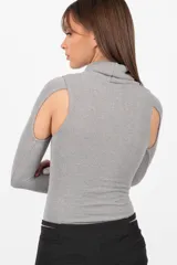 Body gris de tejido de punto con cuello alto y mangas largas. Presenta aberturas en los hombros, broches snap en la entrepierna y elástico interno en el contorno de tiro.