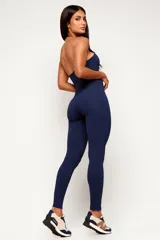 Monopieza deportiva color azul marino, de corte largo, con cuello halter y espalda descubierta.