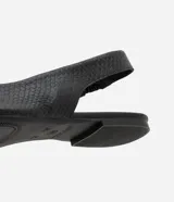 Zapatilla tipo slingback de cuero negro con textura de piel de serpiente, diseño destalonado con tira elástica trasera y punta fina.