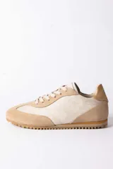 Championes urbanos de diseño retro, confeccionados en una combinación de gamuza y cuero texturizado en tonos beige y arena. Presentan cordones al tono y una suela dentada de goma en color caramelo.