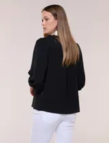 Blusa negra de calce suelto y caída ligera con sutil textura, cuello camisero blanco, escote en V con pechera en contraste y mangas tres cuartos abullonadas con puños elásticos.