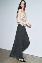 Falda larga de tiro medio, color negro con estampado de lunares blancos. Corte evasé con bajo amplio.