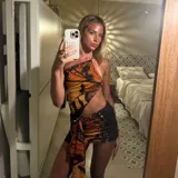 Minivestido con estampado de mariposas en tonos naranja y negro. Diseño ajustado con escote halter asimétrico y abertura en la cintura.