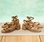 Sandalias de cuero color dorado, con plataforma y taco cuadrado. Presentan tiras cruzadas en el empeine y pulsera al tobillo con hebilla.