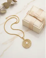Collar de cadena tipo soga en tono dorado con dije circular compuesto por anillos concéntricos incrustados con circonias y una perla central.