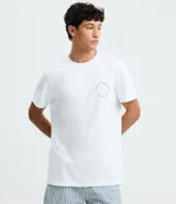 Remera de hombre modelo comfort, color blanco, confeccionada en media malla de algodón y poliéster. Presenta cuello redondo, manga corta y un pequeño estampado circular en el pecho con texto en color celeste.