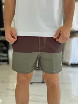 Short de baño con diseño bicolor en tonos gris y rosado, con costuras decorativas visibles en contraste y pequeño aplique circular en el lateral.