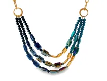 Collar multicapa compuesto por cuentas de cristal facetadas en tonos azules y verdes iridiscentes, combinadas con abalorios dorados y argollas metálicas.