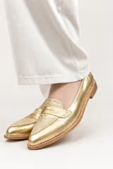 Mocasines de cuero plateado con acabado texturado, diseño clásico con costuras visibles y vira de suela natural cosida. Cuenta con taco plano de 2 cm y plantilla anatómica.