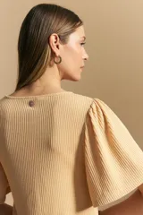 Remera de rib color beige, con cuello redondo y mangas cortas amplias con leve frunce en los hombros. Confeccionada en tejido elastizado de textura acanalada.