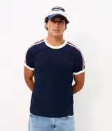 Remera masculina de corte regular, confeccionada en algodón negro, con cuello redondo y mangas cortas con puños blancos. Presenta tiras laterales con rayas en los hombros y mangas.