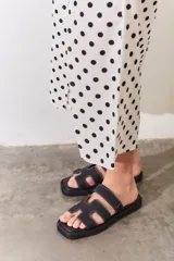Sandalias planas de diseño minimalista en color tostado, con tiras anchas en forma de H y costuras a la vista. Poseen puntera cuadrada y suela plana.