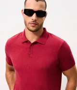 Remera polo de punto color bordó con diseño de rayas horizontales formadas por patrones geométricos blancos, mangas cortas y cierre frontal con tres botones.