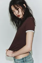 Camiseta negra de manga corta y cuello redondo, con vivos a contraste en el cuello y las mangas.