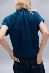 Jersey de punto de textura suave en color azul, con cuello redondo ajustable mediante cordones del mismo tejido y manga corta.