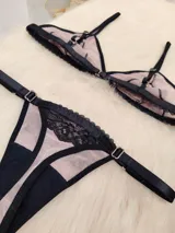 Conjunto de lencería compuesto por un corpiño triangular y una tanga regulable. Está confeccionado en microtul color tostado con detalles de encaje negro en los bordes y en las copas. El corpiño cuenta con breteles finos y la tanga presenta elásticos laterales ajustables.