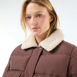 Campera acolchada corta color marrón con cuello de borreguito color crema. Presenta cierre frontal con botones a presión y bolsillos con solapa en el pecho.