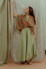 Blusa de algodón con estampado floral multicolor, con detalles en tela a cuadros verde y blanca en el cuello en V, la pechera y los bordes de las mangas cortas.