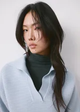 Sweater de punto celeste con cuello polo y cierre frontal en V, manga larga con puños ajustados y diseño acanalado.