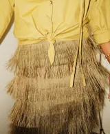 Falda larga de lino color beige con volados de rafia en capas, tajos laterales y cintura elástica en la parte posterior.