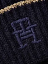 Gorro de lana azul marino con punto canalé y vuelta. Presenta un ribete dorado en el borde inferior y el monograma TH bordado en el frente.